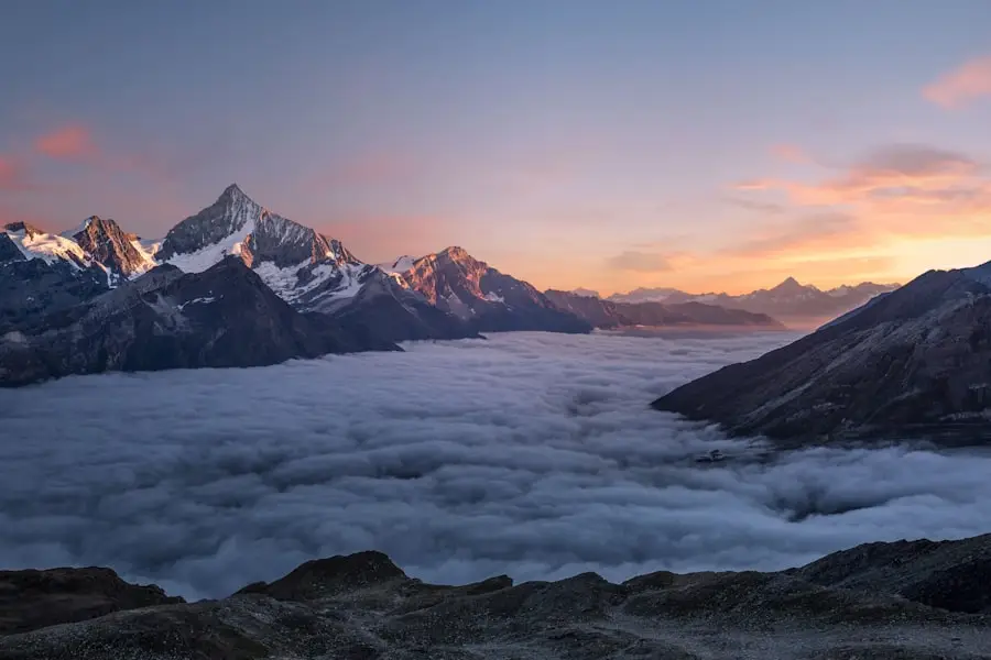 Puncak pegunungan bersalju di atas lautan awan saat senja