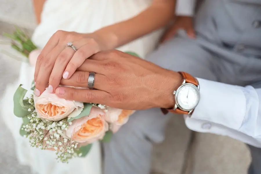 Tangan pengantin bercincin memegang buket bunga mawar